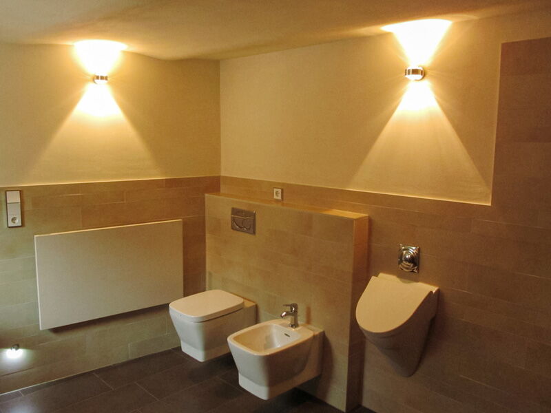 Modernes Bad mit Naturkalkputz, Fliesen und indirekter Wandbeleuchtung