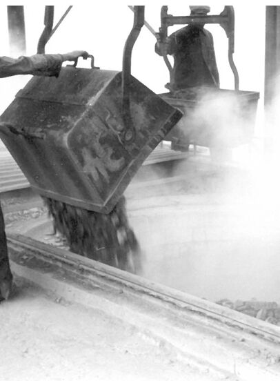 Historische Aufnahme der Kalkproduktion mit Arbeitern beim Entleeren eines Behälters