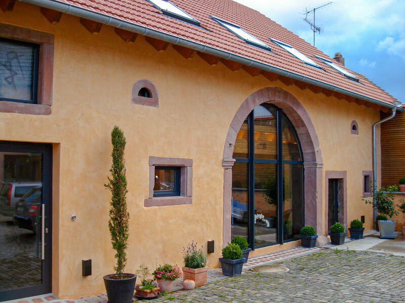 Sanierte Fassade mit Naturkalkputz, Rundbogenportal und Natursteinrahmen