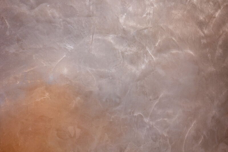 Detailaufnahme einer Naturkalkputz-Oberfläche mit lebendiger Struktur und Farbverläufen